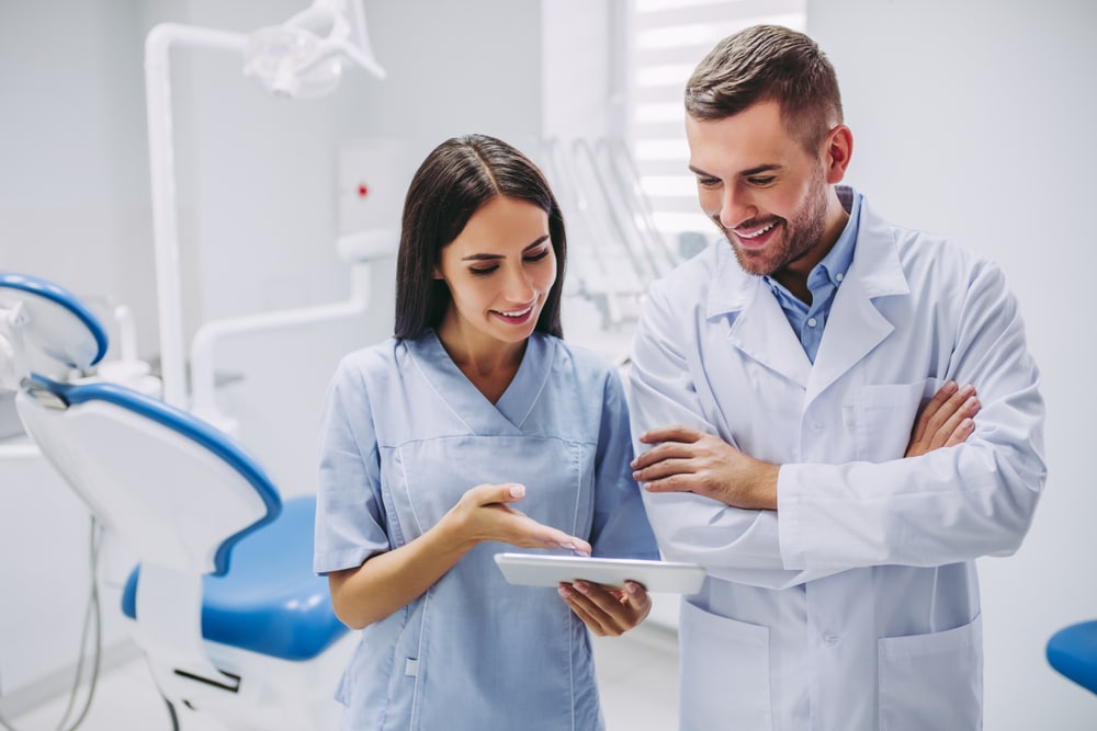 Dentist And Assistant Looking At Digital Tablet Screen