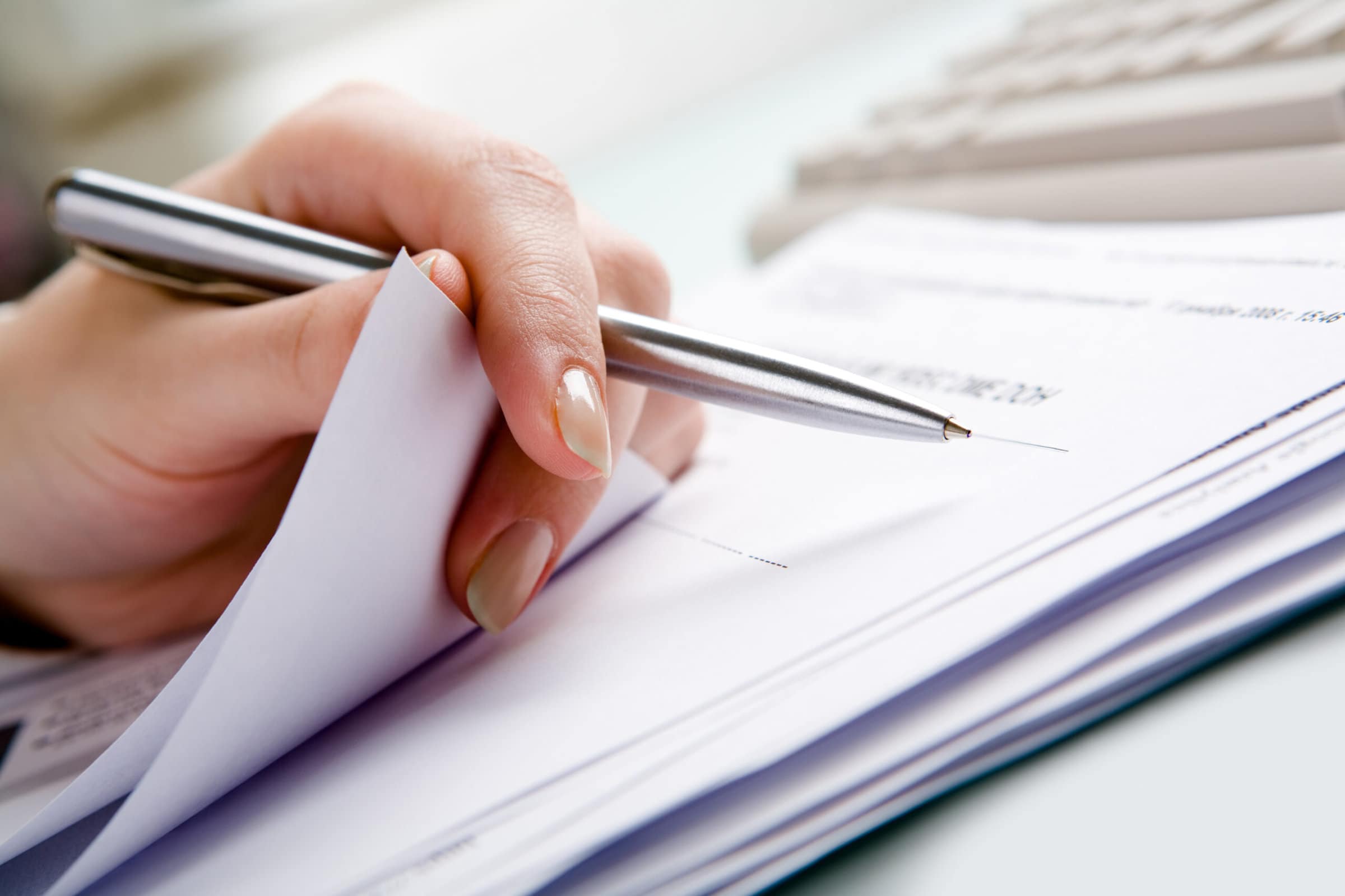 Stock-taking Close-up of hand holding pen with paper over pile of documents