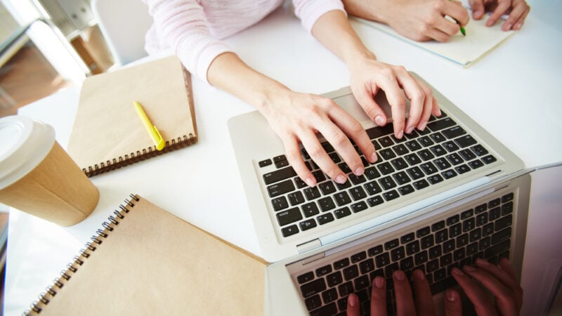 Female student typing on laptop at workplace